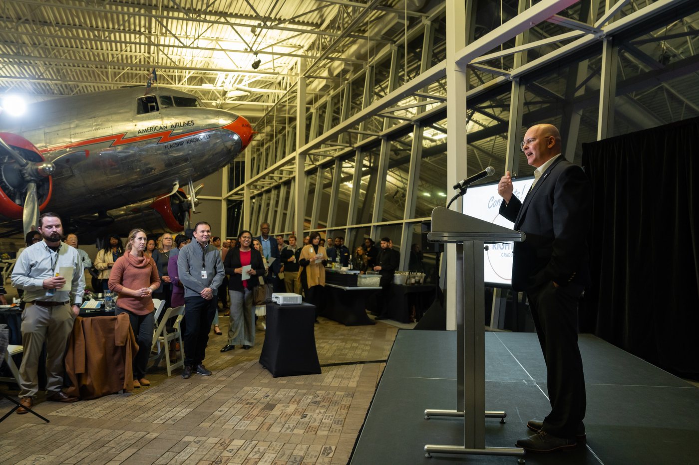 Robert Hausmann facilitating an airline leadership workshop with participants gathered beside a historic aircraft.